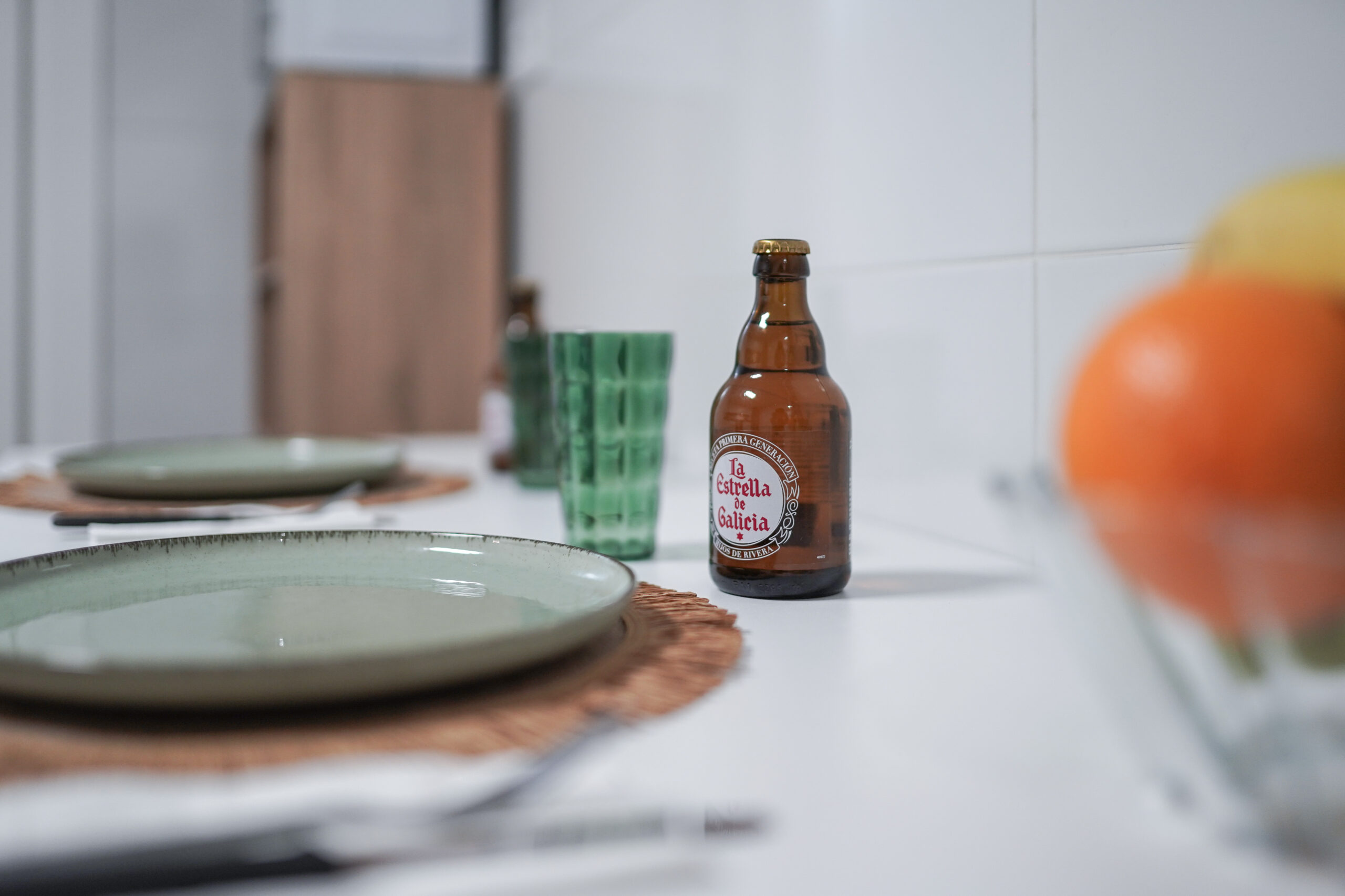 Mesa con platos y botella de cerveza Estrella Galicia al fondo, lista para una comida acogedora.